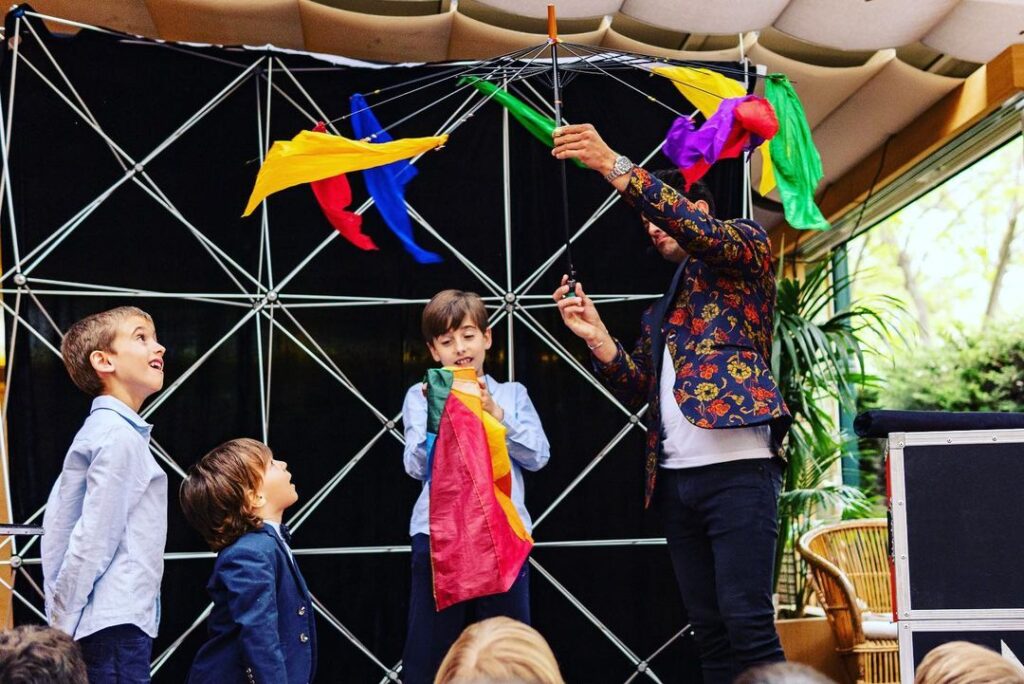 Un mago hace magia para fiestas infantiles con un paraguas con pañuelos